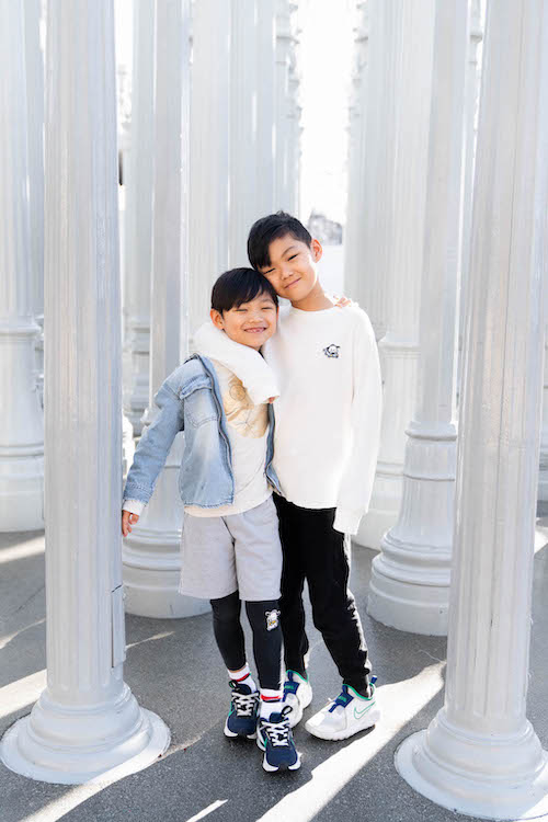 Two young brothers smile and hug each other in Los Angeles on their Flytographer photoshoot.