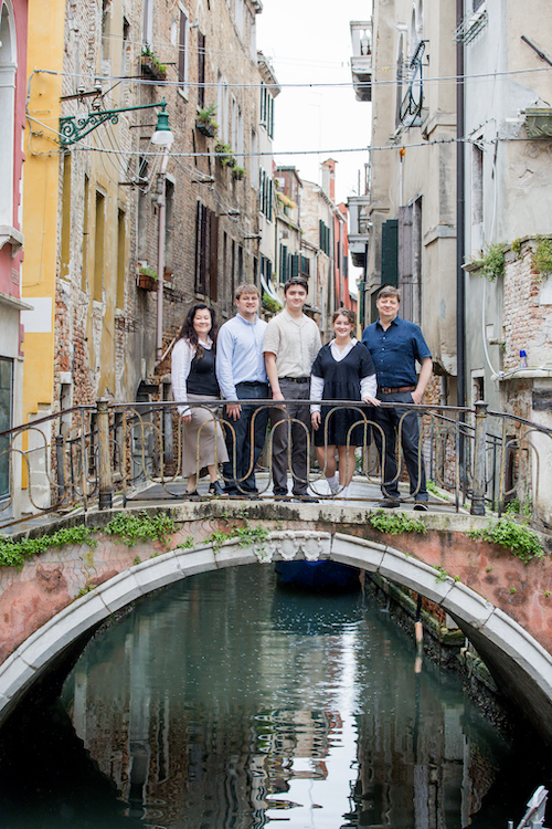 A family poses together on a picturesque canal bridge in Venice on their Flytographer photoshoot.