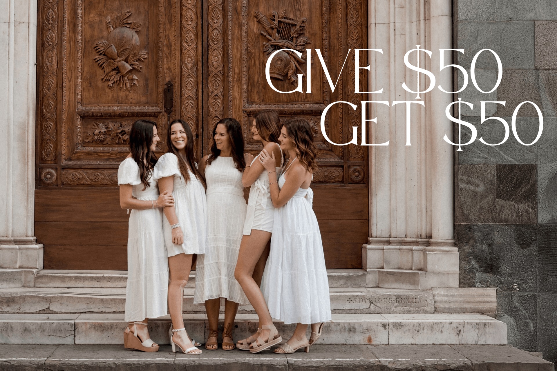 Five women in white dresses pose in front of a door for a Flytographer shoot